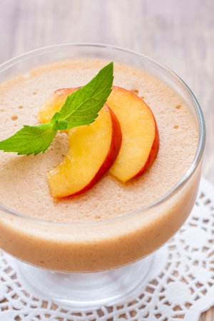 Delicious peach mousse in glass, wooden backrgoundの写真素材
