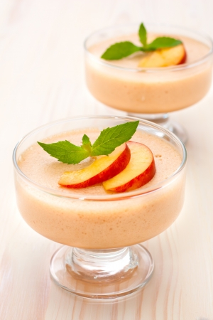 Delicious peach mousse in glass, white wooden backrgoundの写真素材