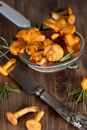 Chanterelles in sieve, wooden backgroundの写真素材