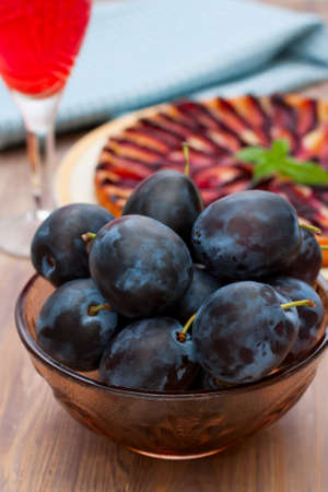Plums in glass bowl  Wooden background