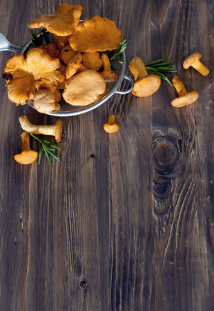 Chanterelles in sieve, wooden backgroundの写真素材