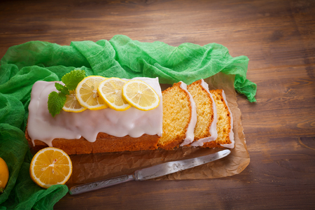 Homemade lemon pound cake with sweet lemon icing on rustic wooden table, sliced.の写真素材