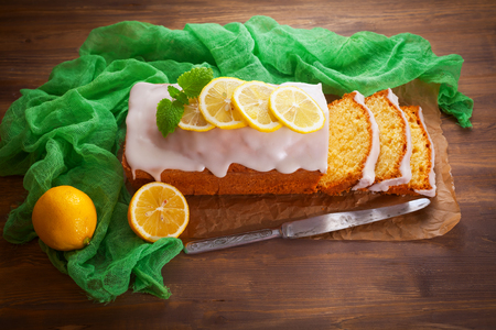 Homemade lemon pound cake with sweet lemon icing on rustic wooden table, sliced.の写真素材