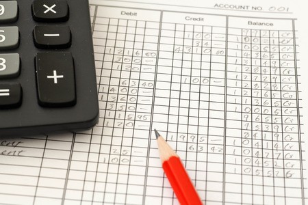 Handwritten Accounting ledger showing bookkeeping using pencil and calculator.の写真素材