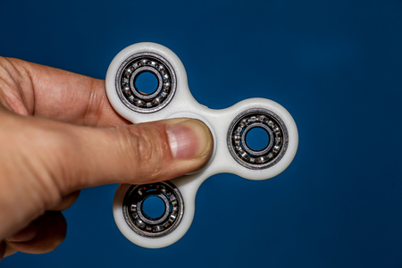 Hand holding a stationary fidget spinner on blue backgroundの写真素材