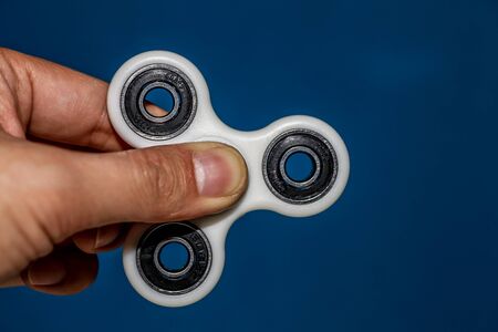 Hand holding a stationary fidget spinner on blue backgroundの写真素材