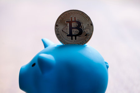 Large Bitcoin being deposited into a piggy bankの写真素材