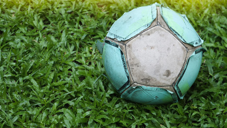Football on the lawn. Old ball on beautiful green grass on fieldの写真素材