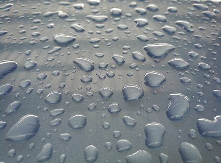 Water drop  of rain on a blue car backgroundの写真素材