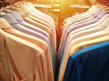 blurred mens shirts in different colors on hangers in a retail clothes storeの写真素材