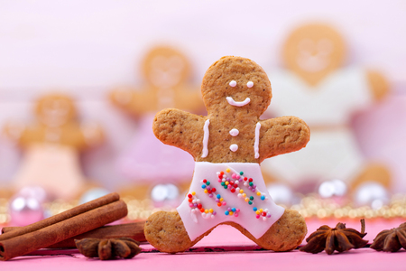 Homemade baked Christmas gingerbread man on vintage wooden background. Anise, cinnamon and decoration utensils.の写真素材