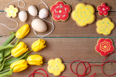 Homemade baked gingerbread, Easter eggs and tulips on vintage wooden background