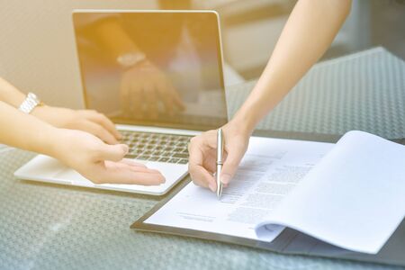 Female hand signing contract, Human hands working with documents at the desk closeup, Two business partners signing a document, Selective focus.の写真素材