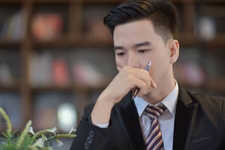 Young attractive Asian business man sleeping, drowsing or taking a nap at her desk, Tired business man accountant with bills and paper folders in office, tired young business woman with laptop.の写真素材