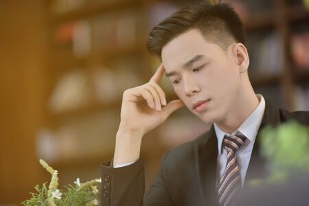 Young attractive Asian business man sleeping, drowsing or taking a nap at her desk, Tired business man accountant with bills and paper folders in office, tired young business woman with laptop.の写真素材