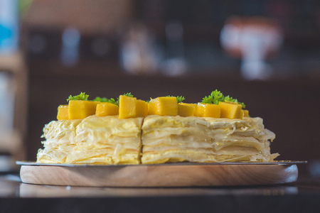 close up mango crepe with fresh mango, creamy mango mousse cake on a white wood background. toning. selective focus, Mango cheesecake on white plate with forkの写真素材