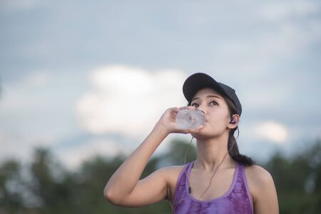 Selective focus Young woman engaged in sports. Take a resting and drinking water.