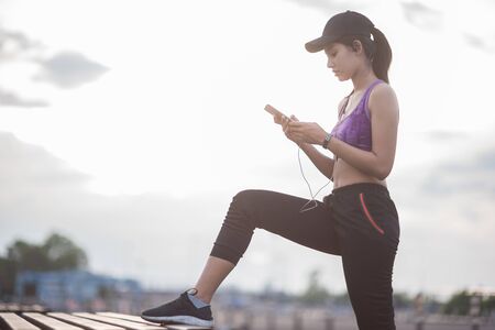 Smiling of Asia woman athlete sitting on an exercise mat and stretching in a field.の写真素材
