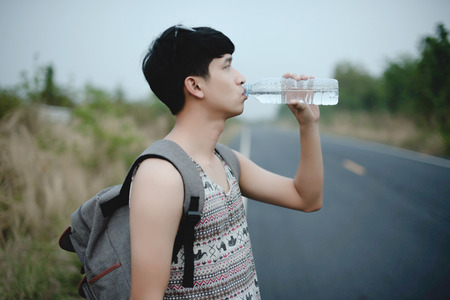 loner walking down an empty road and hot. Road hitch-hiking.