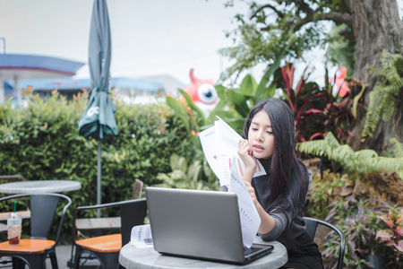 Young attractive Asian business woman sleeping, drowsing or taking a nap at her desk, Tired business woman accountant with bills and paper folders in office, tired young business woman with laptop.の写真素材