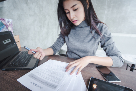 Young pretty joyful brunette woman meditating on table surround work stuff and flying papers. Cheerful mood, taking a break, working, studying, relaxation, true emotionsの写真素材