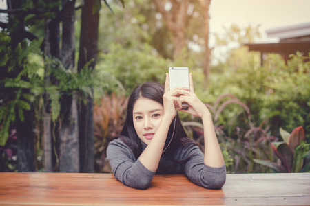 Portrait of young businesswoman use mobile phone while sitting in comfortable coffee shop during work break, charming happy female reading fashion news on cell telephoneの写真素材