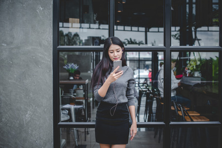 Portrait of young businesswoman use mobile phone while sitting in comfortable coffee shop during work break  charming happy female reading fashion news on cell telephoneの写真素材