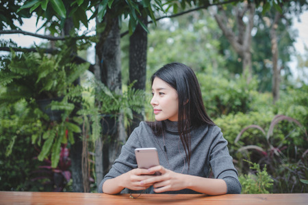 Portrait of young businesswoman use mobile phone while sitting in comfortable coffee shop during work break, charming happy female reading fashion news on cell telephoneの写真素材