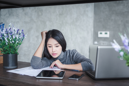 Young attractive Asian business woman sleeping, drowsing or taking a nap at her desk, Tired business woman accountant with bills and paper folders in office, tired young business woman with laptop.の写真素材