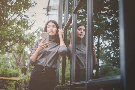 Portrait of young businesswoman use mobile phone while sitting in comfortable coffee shop during work break  charming happy female reading fashion news on cell telephoneの写真素材