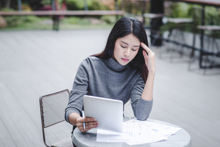 Business woman holding a tablet computer stressed because of falling stock