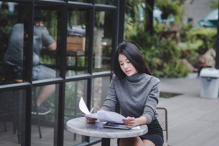 Young stressed woman sitting at desk in a little office or home mad at work, ripping documents with frustrated facial expression. Throwing around scraps of paper. Negative human emotionsの写真素材