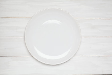 Empty plate top view on white plank wooden backgroundの写真素材