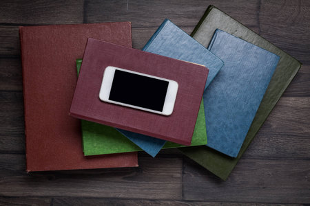 Book and smartphone, top view on wooden background, desk.の写真素材