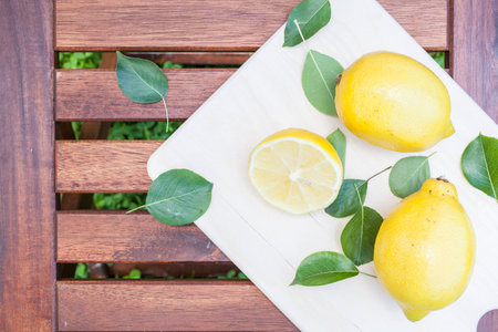 lemon fruit on wood cutting board top view with green leaf backgroundの写真素材