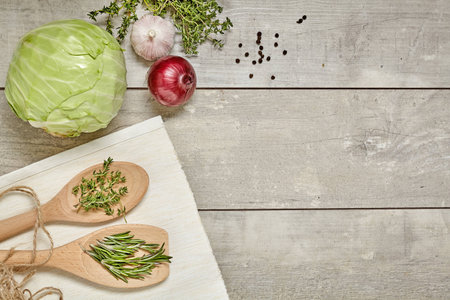 Wooden spoon with Caraway and rosemary, cabbage, onion, garlic on wooden background. Top view.の写真素材
