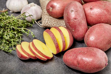 Red potato on black wood table in kitchen. With spice and garlic.の写真素材