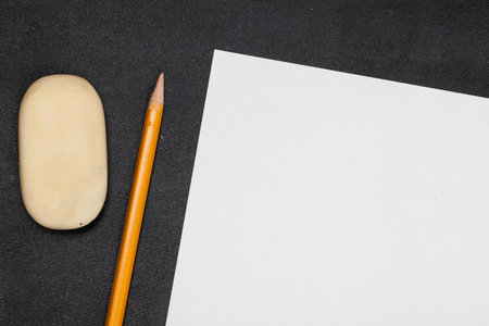 Blank paper and pencils with eraser on the black wooden table. View from above