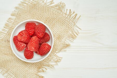Fresh red raspberry on wooden background with napkin..