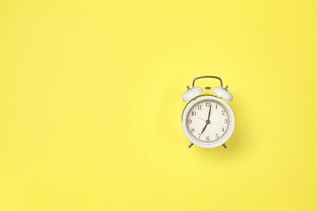 White alarm clock on yellow background