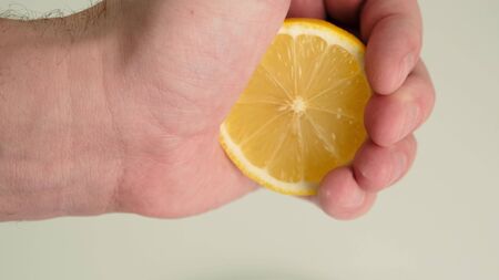 Female hand squeezing juice from fresh lemon. Close up.の写真素材