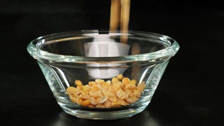 Dried peas are poured on glass bowl on black background. Close up.の写真素材
