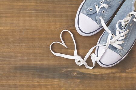 Sneakers on wooden background. Laces shape heart.