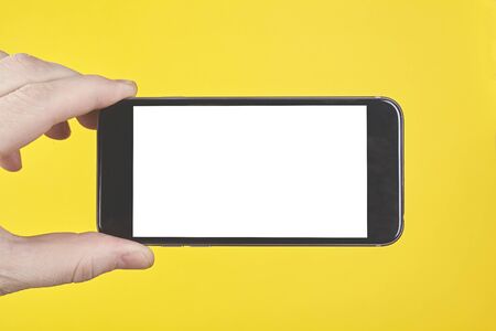Hand hold smartphone on yellow background.の写真素材