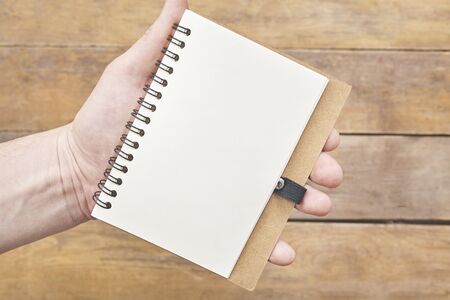 Hand with notebook blank paper over wood table.の写真素材