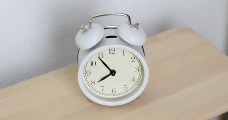 Mens hands off ringing white alarm clock. Close up.