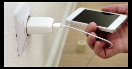 white smartphone on charge. Connecting cable to the phone. Close up.