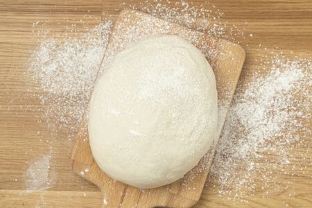 Raw dough for bread or pizza on a wooden background. Top view