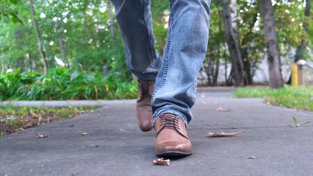 View of man's walking legs in blue jeans, black leather shoes. Close up.の写真素材