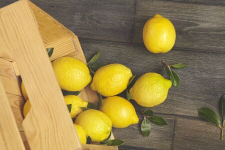 Wooden box of fresh lemons with tree leaves. Top view.の写真素材